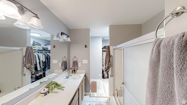 full bathroom featuring a spacious closet, vanity, and a shower with door