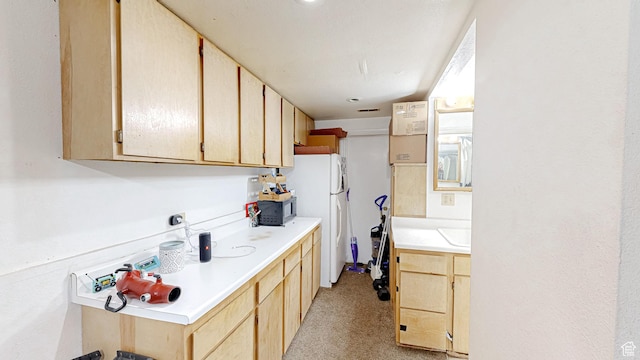 kitchen with light countertops, freestanding refrigerator, black microwave, and light brown cabinetry