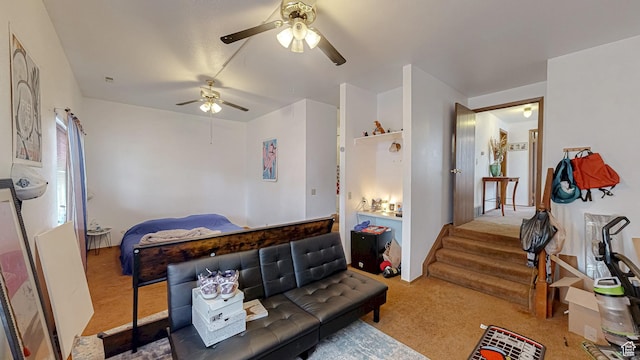 carpeted living room with ceiling fan and stairs