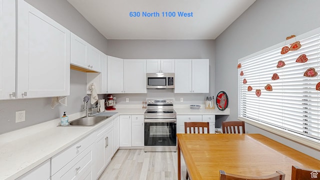 kitchen featuring appliances with stainless steel finishes, a sink, white cabinetry, and light countertops