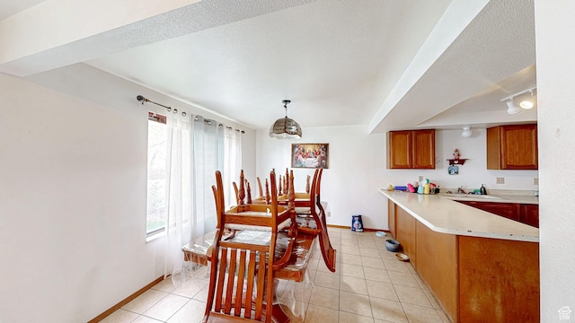 dining area with light tile patterned flooring, a textured ceiling, rail lighting, and baseboards