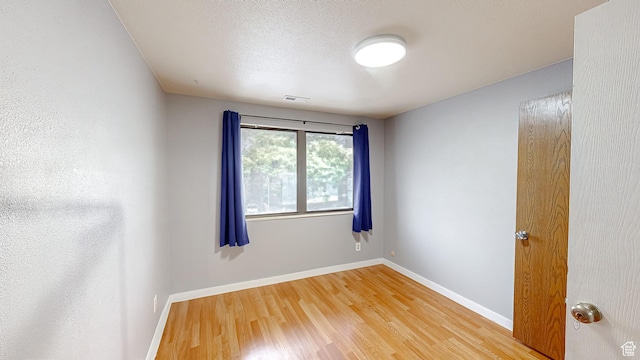 spare room featuring light wood-type flooring, baseboards, and visible vents