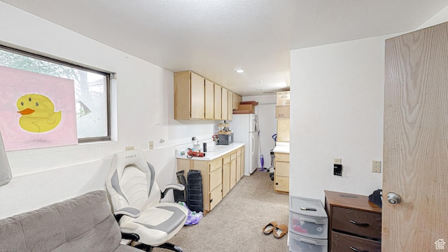 kitchen featuring light countertops, freestanding refrigerator, light brown cabinets, and light carpet