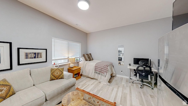 bedroom featuring vaulted ceiling, wood finished floors, visible vents, and baseboards