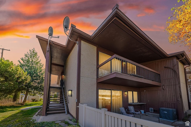 back of property with stucco siding, stairway, a balcony, and fence