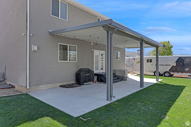rear view of house with stucco siding, a yard, a patio, and entry steps