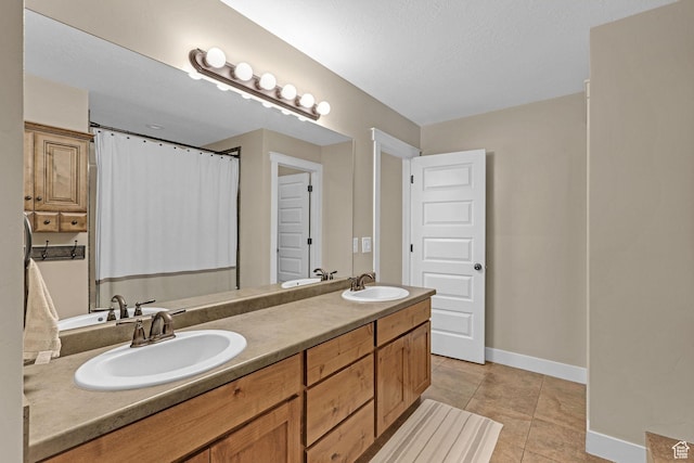bathroom with tile patterned flooring, baseboards, a sink, and double vanity