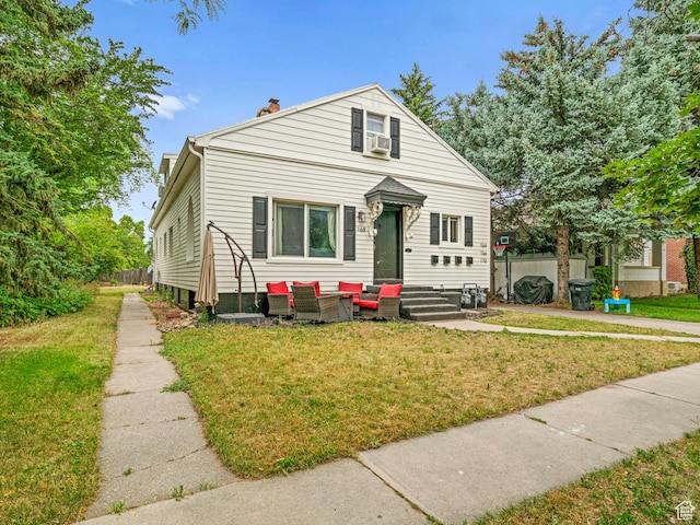 bungalow-style house with a chimney, a front lawn, an outdoor living space, and cooling unit