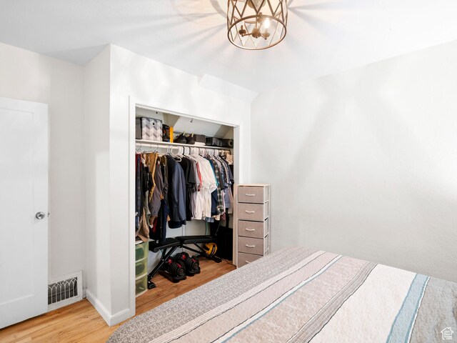 bedroom with a closet, wood finished floors, visible vents, and baseboards