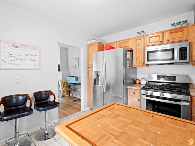 kitchen with light countertops, appliances with stainless steel finishes, baseboards, and light tile patterned floors