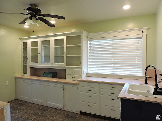 kitchen with white cabinets, a wealth of natural light, a ceiling fan, and a sink