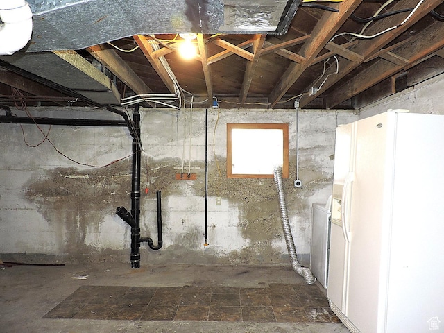 below grade area featuring white refrigerator with ice dispenser
