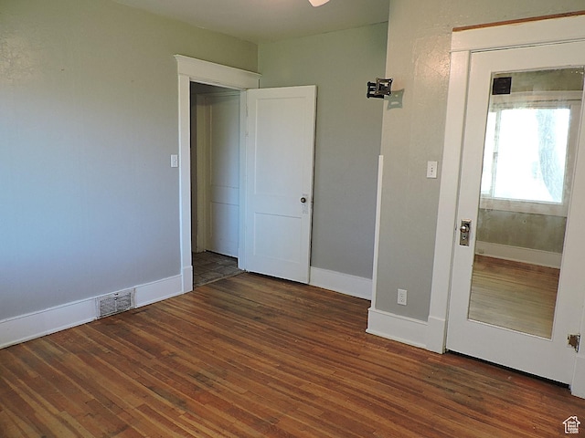 unfurnished bedroom featuring baseboards, wood finished floors, and visible vents