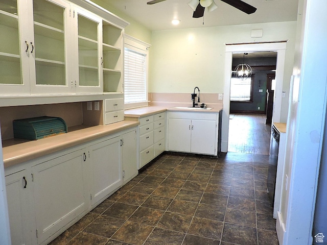 kitchen featuring a sink, glass insert cabinets, ceiling fan, light countertops, and white cabinets
