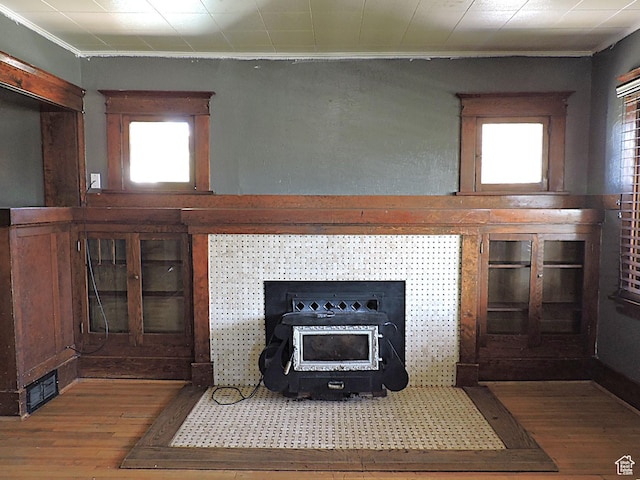 room details featuring crown molding, a wood stove, wood finished floors, and visible vents