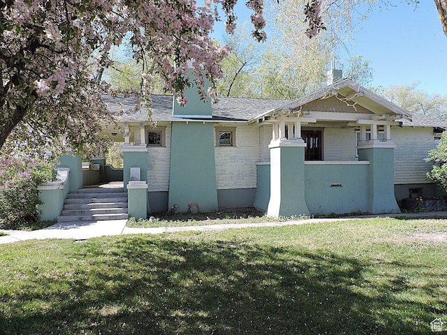 view of front facade featuring a front lawn and a shingled roof