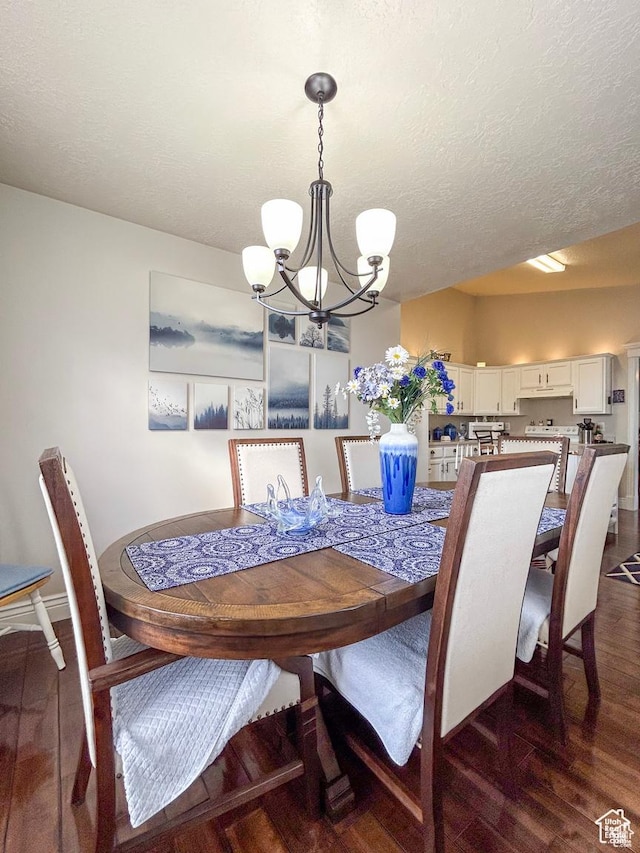 dining space with dark wood finished floors, a textured ceiling, baseboards, and a notable chandelier