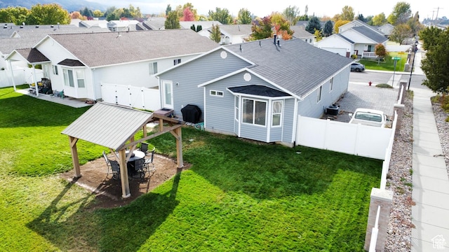 rear view of house featuring a residential view, a fenced backyard, a gazebo, a patio area, and a lawn