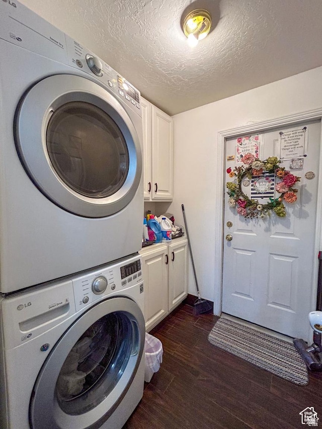 laundry area with dark wood finished floors, cabinet space, stacked washer / dryer, and a textured ceiling