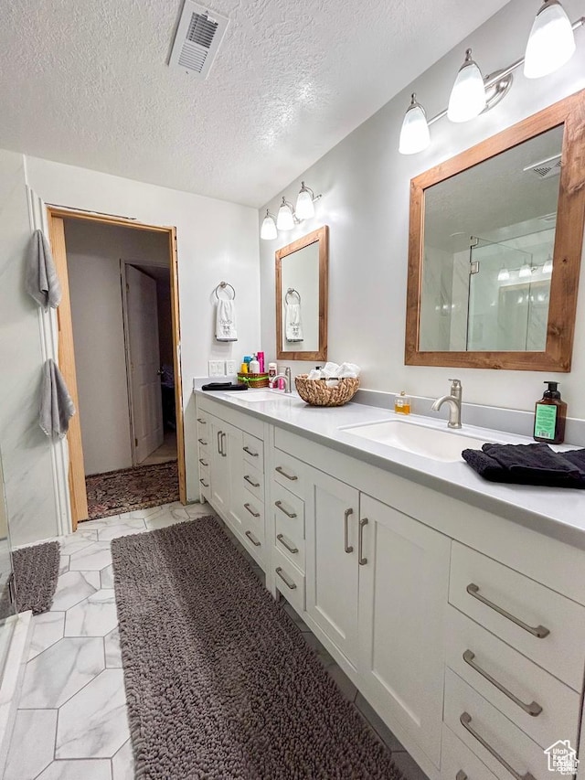 bathroom featuring marble finish floor, visible vents, a sink, and a shower stall