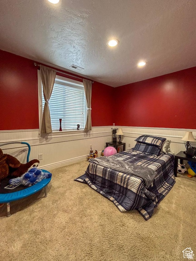 bedroom featuring recessed lighting, a wainscoted wall, a textured ceiling, and carpet