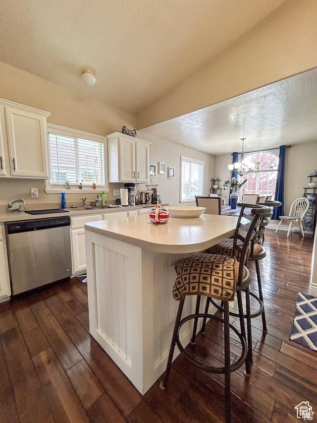 kitchen featuring light countertops, dark wood finished floors, dishwasher, and white cabinetry