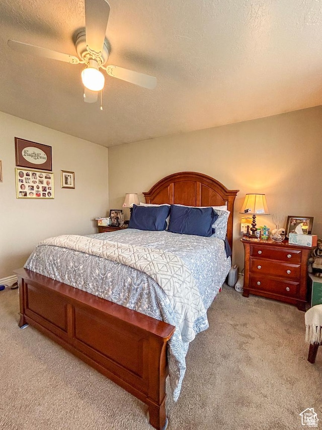 carpeted bedroom with a ceiling fan and a textured ceiling