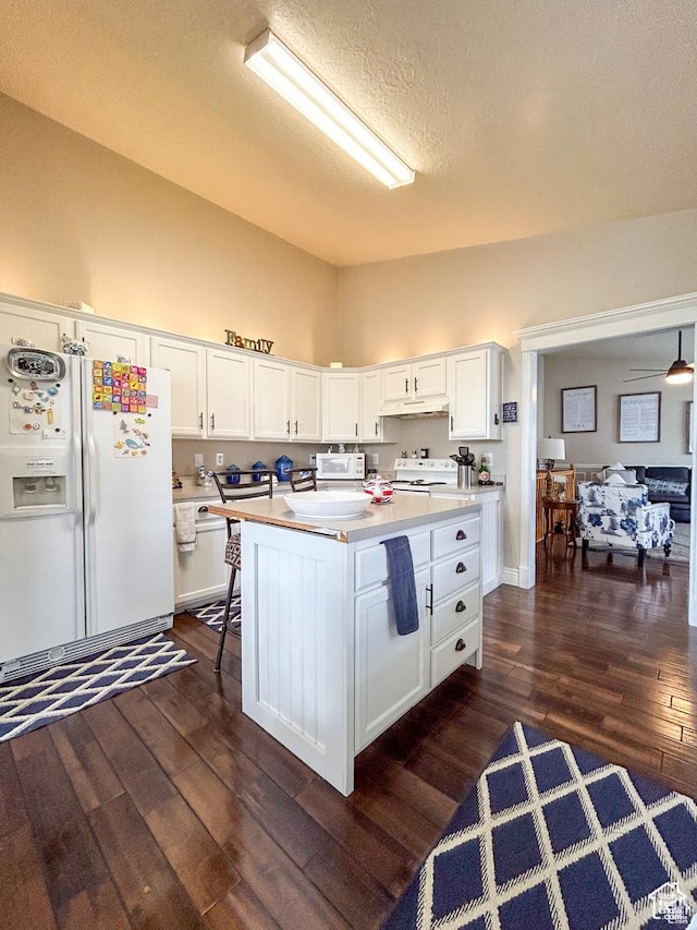 kitchen with under cabinet range hood, white appliances, white cabinetry, and dark wood finished floors