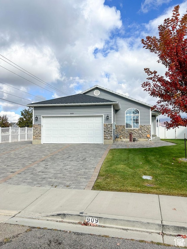 ranch-style home with stone siding, fence, a front yard, and a garage