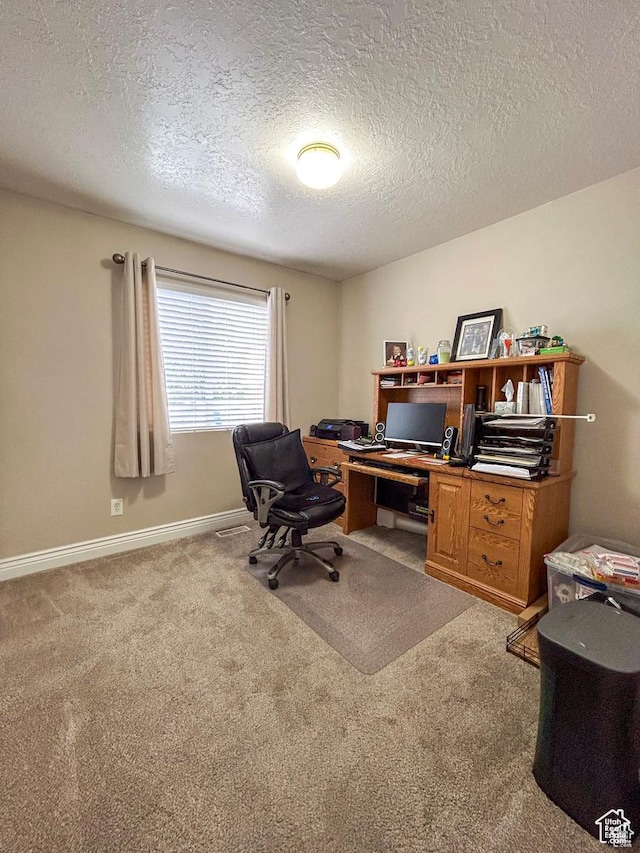 carpeted office featuring a textured ceiling and baseboards