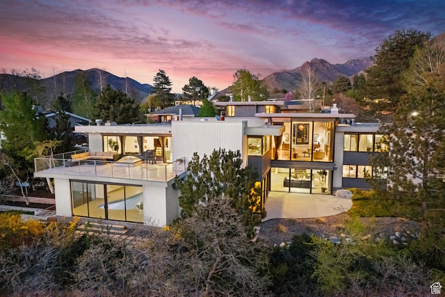 back of house with a patio area, a chimney, a balcony, and a mountain view