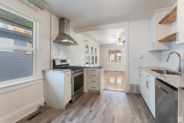 751 E Browning Ave S, Salt Lake City, UT 84105 - kitchen with stainless steel appliances, wall chimney range hood, a sink, light wood-style floors, and tasteful backsplash