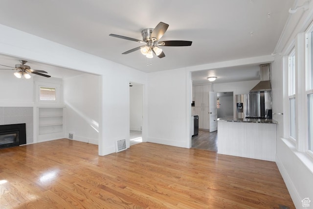 751 E Browning Ave S, Salt Lake City, UT 84105 - unfurnished living room featuring ceiling fan, a fireplace, visible vents, and light wood-type flooring