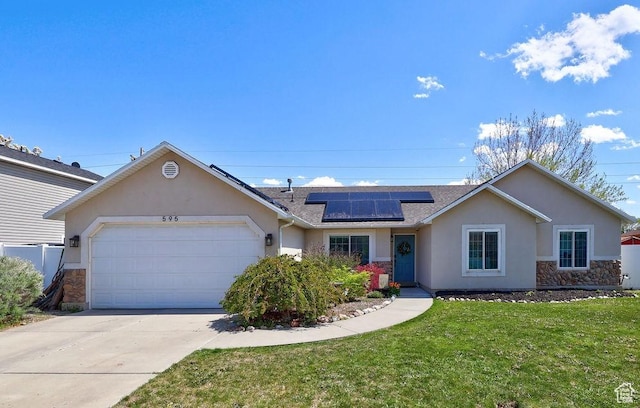 ranch-style house featuring solar panels, stone siding, an attached garage, a front yard, and stucco siding