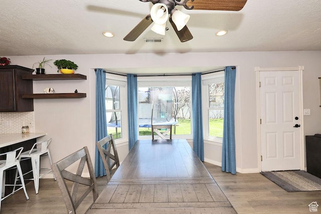 interior space with light wood-style floors, visible vents, a ceiling fan, and a wealth of natural light
