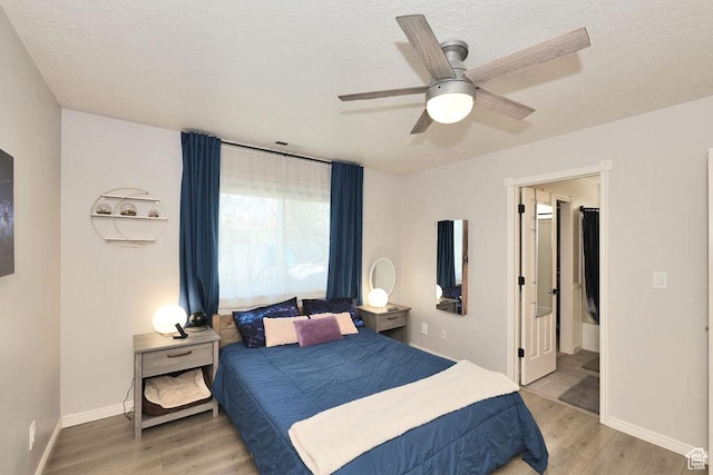 bedroom with light wood-style flooring, baseboards, and a textured ceiling