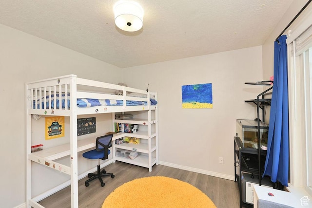 bedroom with wood finished floors, a textured ceiling, and baseboards