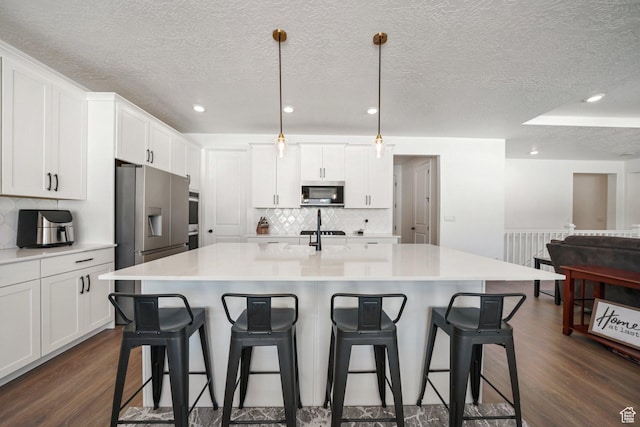 788 N 2100 E, Spanish Fork, UT 84660 - kitchen featuring a breakfast bar, dark wood finished floors, stainless steel appliances, white cabinetry, and decorative backsplash