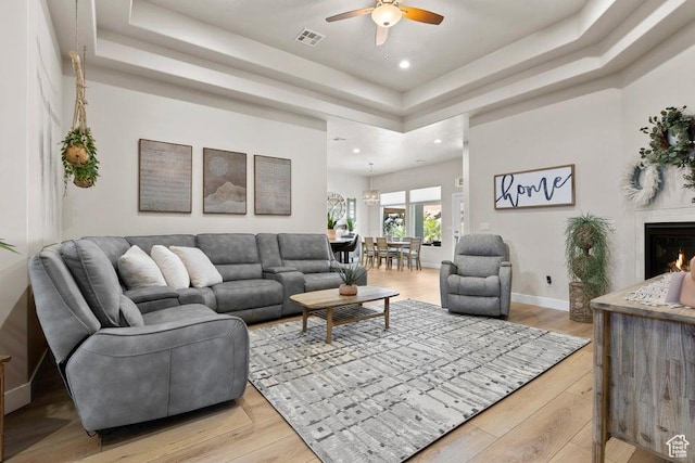 1920 W 180 N, Hurricane, UT 84737 - living area with light wood finished floors, a tray ceiling, a warm lit fireplace, visible vents, and ceiling fan