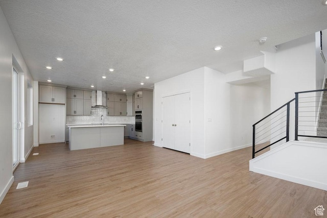 912 W Bellshill Dr Unit 15, Murray, UT 84123 - kitchen with wall chimney exhaust hood, gray cabinets, a textured ceiling, tasteful backsplash, and light wood-style floors