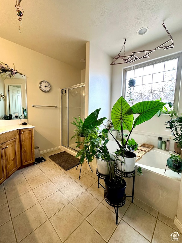full bathroom featuring a bath, a textured ceiling, a stall shower, tile patterned flooring, and vanity
