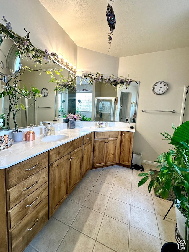 bathroom with a textured ceiling, tile patterned flooring, a stall shower, and vanity