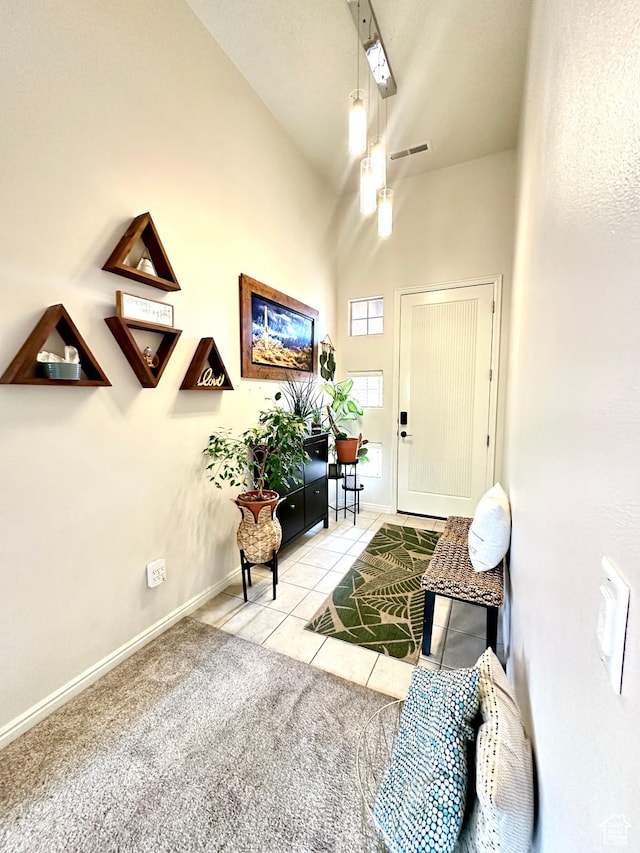 foyer with high vaulted ceiling, visible vents, tile patterned flooring, and baseboards