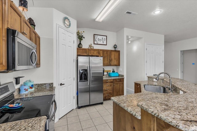 240 W 225 S, Ivins, UT 84738 - kitchen featuring stainless steel appliances, brown cabinetry, light tile patterned floors, light stone countertops, and a textured ceiling