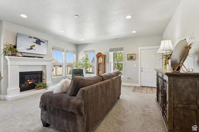 living room with light carpet, baseboards, a glass covered fireplace, and recessed lighting