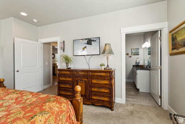 bedroom featuring light carpet, baseboards, and a sink
