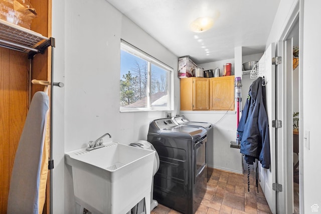 laundry area with baseboards, stone finish flooring, separate washer and dryer, a sink, and cabinet space