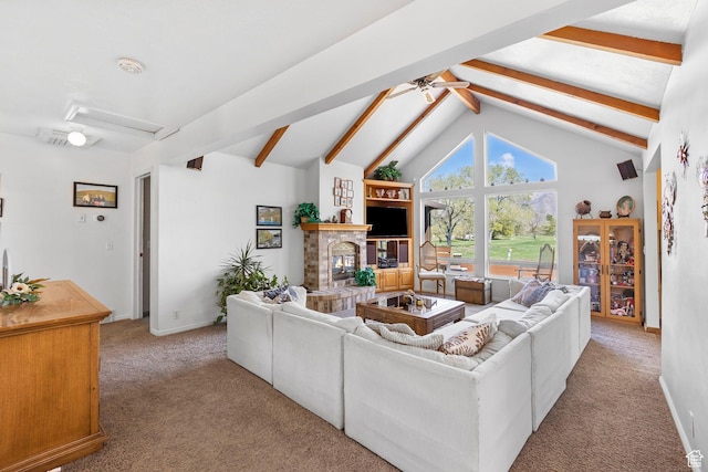carpeted living room with a ceiling fan, a glass covered fireplace, lofted ceiling with beams, and attic access