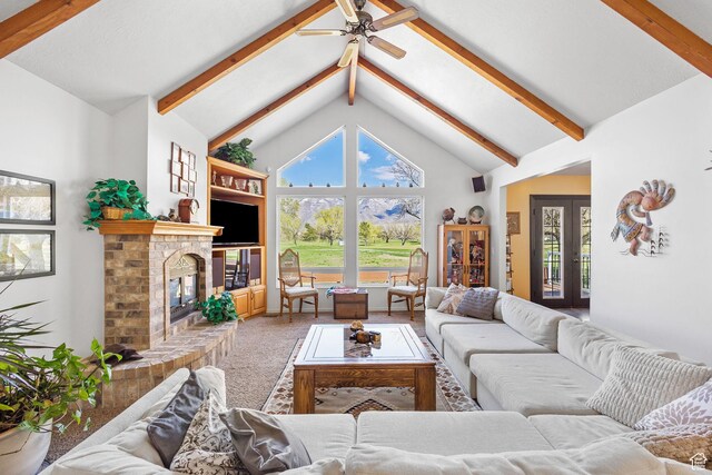 carpeted living area featuring a brick fireplace, ceiling fan, high vaulted ceiling, and beamed ceiling