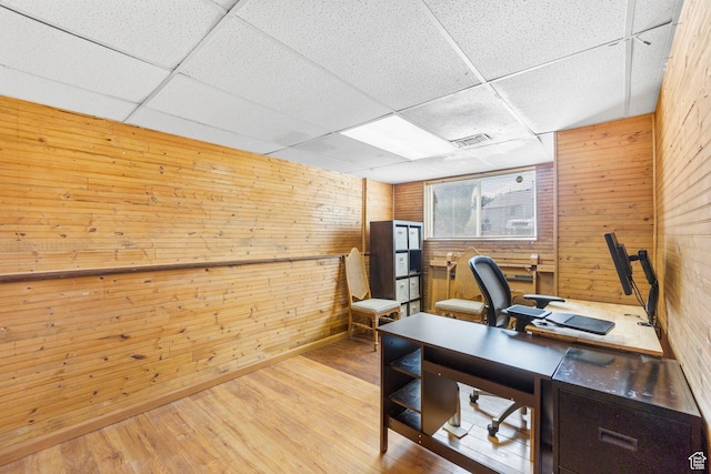 office with visible vents, wood walls, a drop ceiling, and wood finished floors